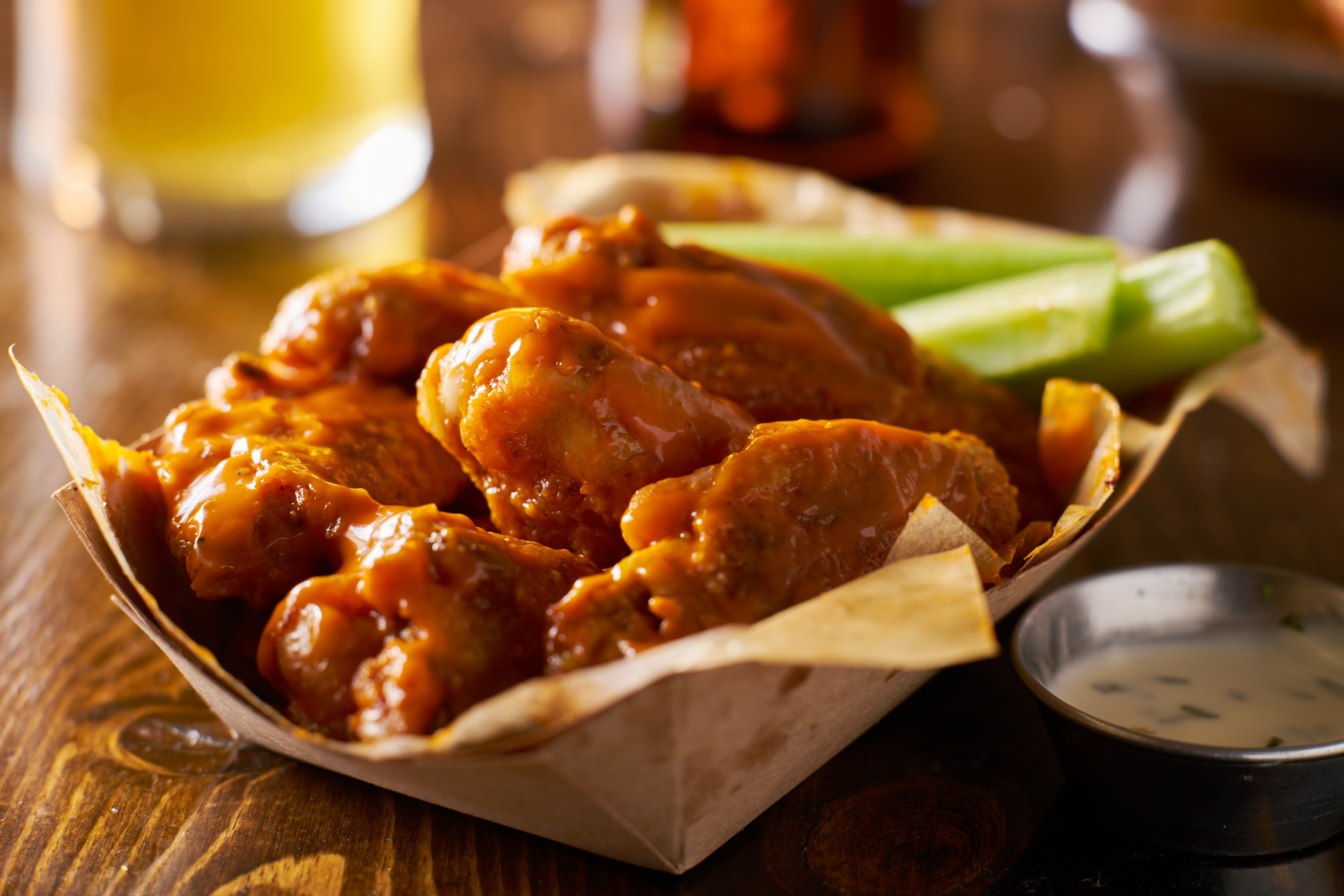 pile of tasty buffalo chicken wings in paper tray with celery and beer
